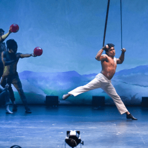 Aerialist on silks on a blue lit stage