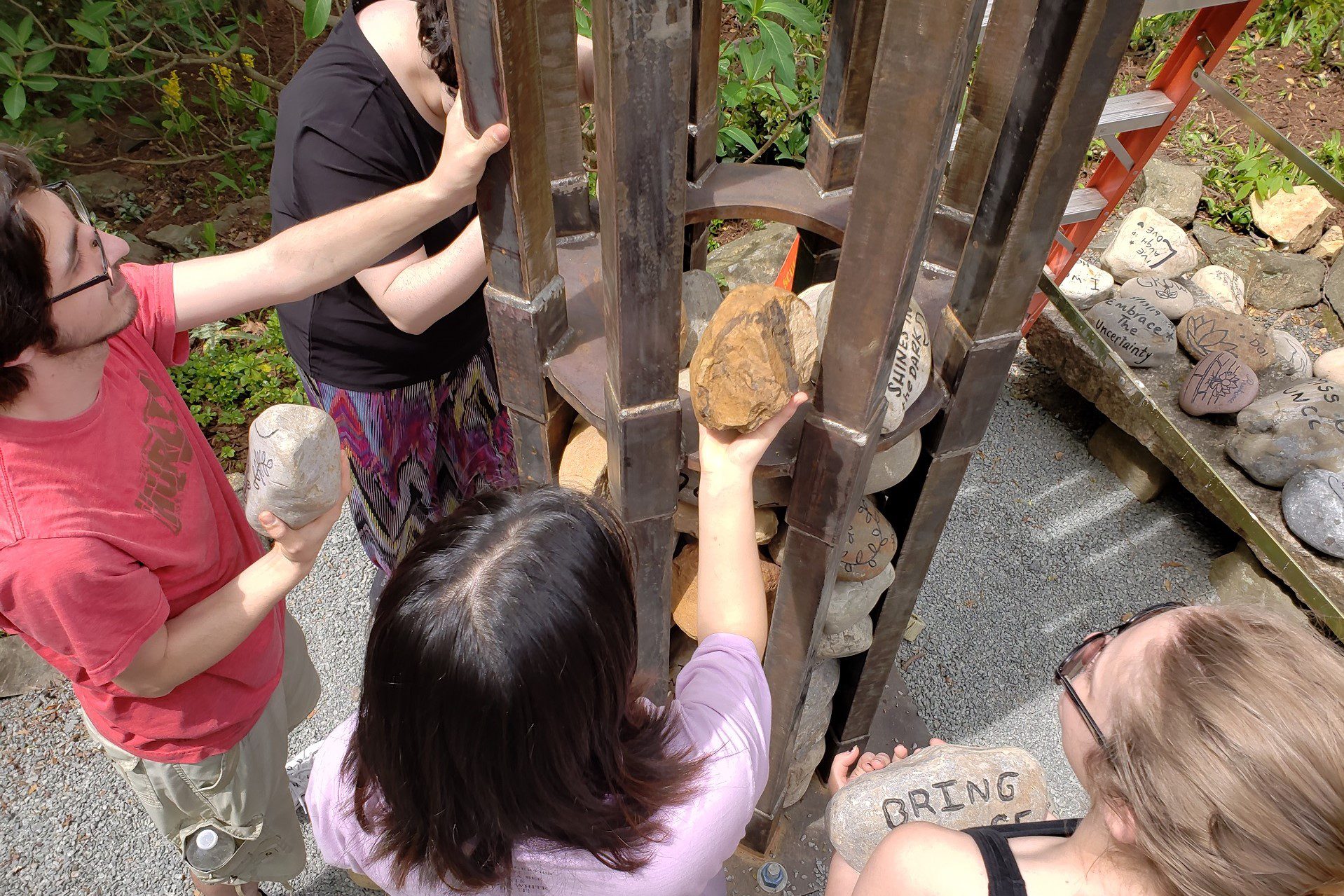 students putting rocks in memorial sculpture