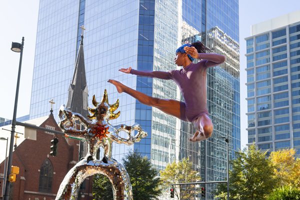 Alabi jumping in front of a city landscape