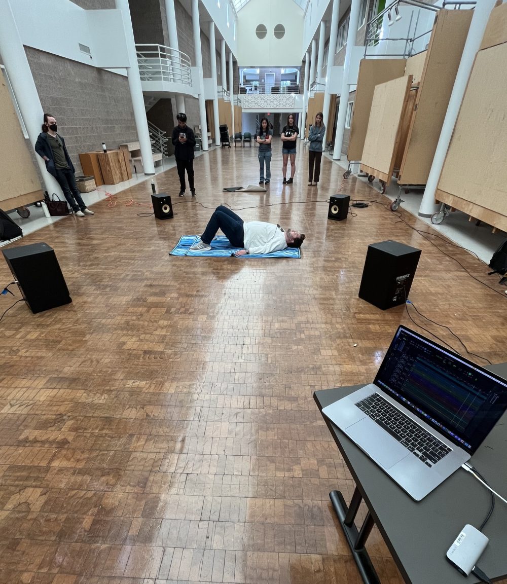 Student lying on floor in Storrs salon for spatial audio workshop.